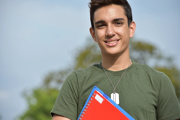 Student smiling holding a notebook and folder