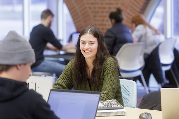 Two students studying at a table in the library